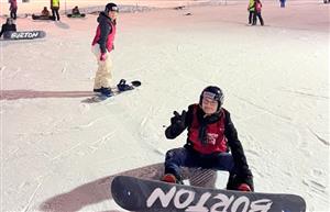 student attached to a snowboard sitting on the snowy ground